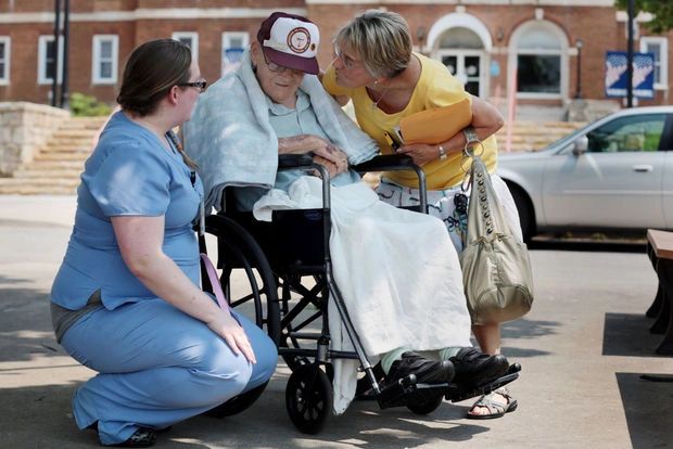 Caregiver with elderly person in wheelchair outdoors