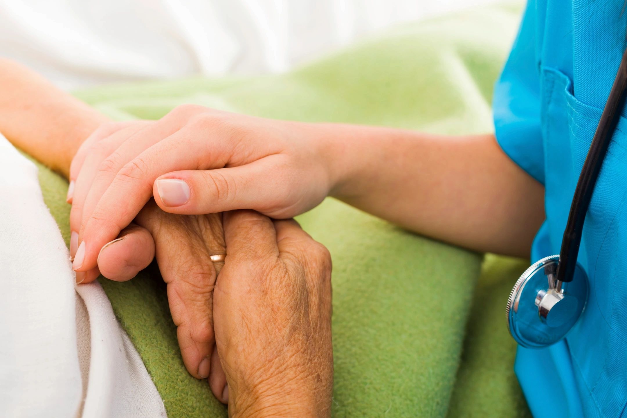 Caregiver gently holding elderly patient's hands